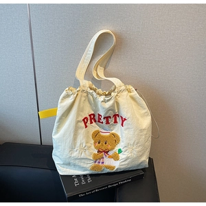 Detail of off-white drawstring tote with sailor bear embroidery and red Pretty lettering
