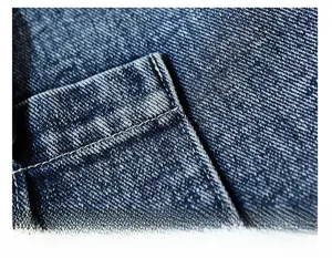 Detail of neat stitching on dark blue denim shoulder bag with washed texture
