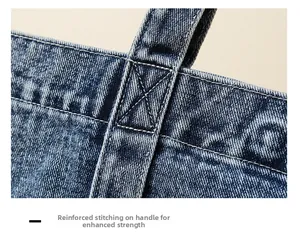 Detail showing cross-stitched reinforced handles on denim tote bag for durability