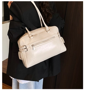 Detail view of a creamy white bowling tote bag featuring a front zipper and large capacity