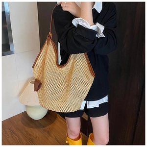 Detailed close-up of woven straw tote bag with brown leather trim and handles