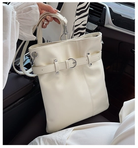Detail of cream pleated bucket bag with decorative silver buckle and adjustable strap