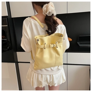 Rear view of a pale yellow pleated drawstring backpack with silver hardware on a model