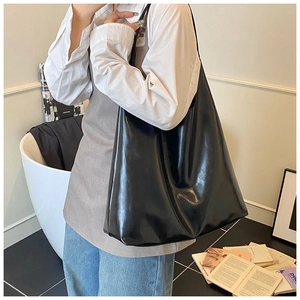 Detail of a large black glossy PU leather tote bag worn by a model for a chic commute style
