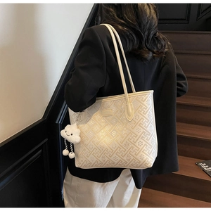 Détail du sac cabas crème avec broderie florale et charm en forme de nuage blanc