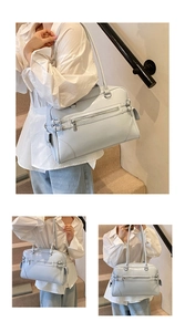 Detail of light blue structured tote bag with functional zippers and utility straps