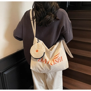 Detail of off-white canvas tote bag with orange logo and matching small round purse