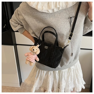 Mini sac cabas noir minimaliste en cuir gaufré brillant avec un charme de chiot en peluche