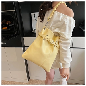 Close-up of bright yellow pleated bucket bag featuring metallic buckle and ring detail