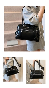Detail of glossy black patent leather bowling bag with twin handles and metal buckles