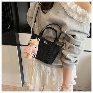Petit sac fourre-tout noir avec breloque ours en peluche et lettrage blanc porté en bandoulière