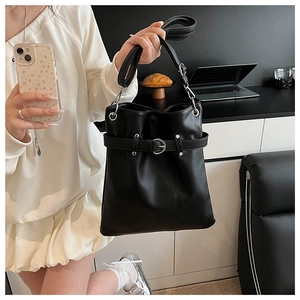 Detail of black PU leather bucket bag featuring decorative silver metal buckle and strap