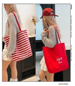 Vue lifestyle de grands sacs cabas en toile rouges et rayés avec broderies de lettres