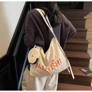 Detail of off-white canvas tote bag with orange graphic text and mini round coin purse