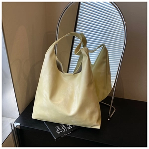 Macro detail of the pale yellow tote bag made from glossy faux leather in a chic interior setting