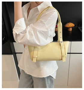 Détail d'un sac sous le bras en cuir jaune clair avec une boucle de ceinture argentée chic