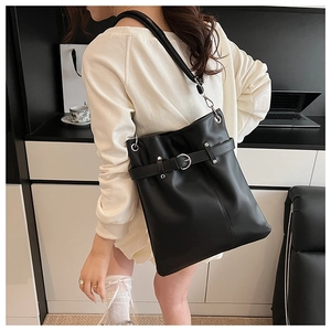 Detail view of large black bucket bag showing matte leather texture and silver buckle