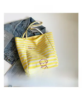 Détail d'un sac cabas en toile rayé jaune avec broderie de chien et texte élégant