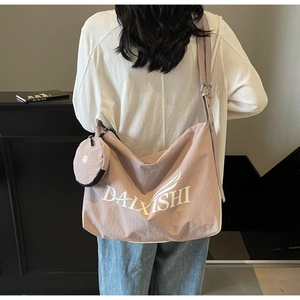 Detail view of pink canvas crossbody bag with adjustable strap and small round pendant