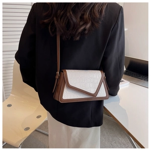 Close-up of a white crocodile texture crossbody bag paired with a black blazer outfit