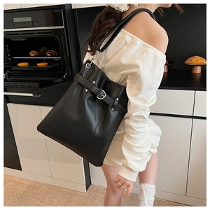 Detail of black large capacity leather tote bag with silver buckle and belt decoration