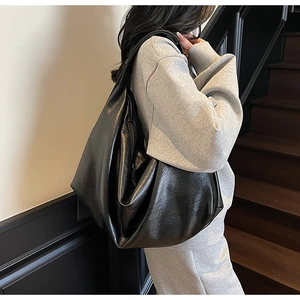 Detail of the large black hobo bag showing the high-shine soft leather and natural texture