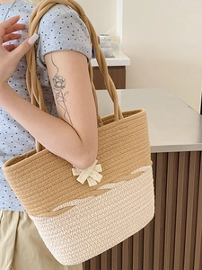 Two-tone woven straw tote bag with bow detail for summer beach travel and vacation