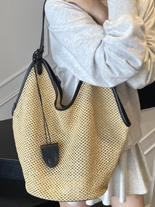 Minimalist woven straw bucket bag with black leather straps for summer beach style