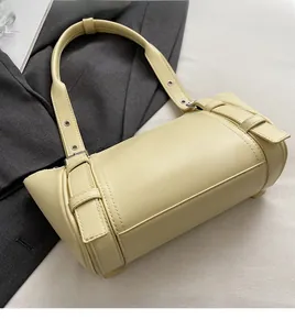 Gros plan du sac boston en cuir crème avec détail de boucle et bandoulière réglable