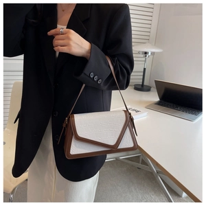 Detail of color-block baguette bag in white faux croc leather and brown trim on a model