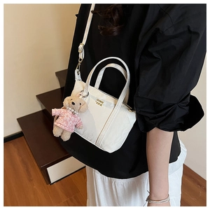 Vue détaillée du mini sac cabas blanc avec logo doré et porte-clés ours en peluche