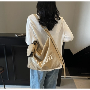 Detail view of khaki canvas tote bag with adjustable strap and small round pouch