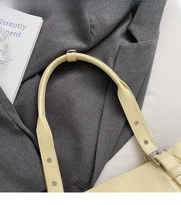 Détail de la bandoulière réglable en cuir crème avec boucle argentée polie et surpiqûres