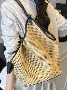 Fashionable large straw hobo shoulder bag with black leather straps and heart pendant
