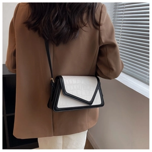 Detail of a chic black and white contrast shoulder bag with faux crocodile skin texture