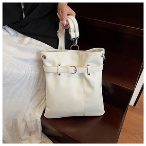 Detailed view of white leather bucket bag with silver metal buckle and adjustable strap