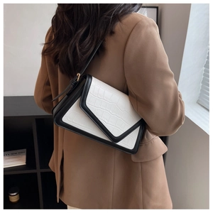 Detail of a vintage contrast shoulder bag with faux crocodile pattern and black V-flap