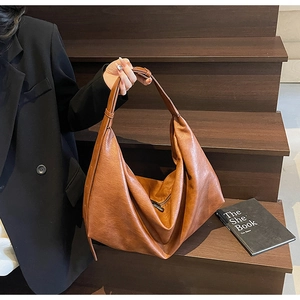 Detail of adjustable wide shoulder strap on brown faux leather hobo shoulder bag