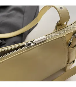Détail d'une fermeture éclair argentée sur un sac à bandoulière en cuir jaune