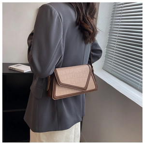 Detail of brown contrast patchwork shoulder bag with crocodile texture on model