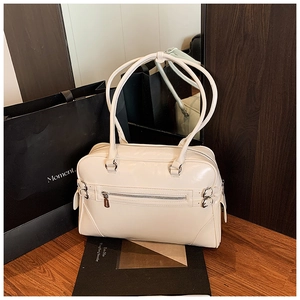 Detail of a minimalist cream bowling bag with glossy leather texture and silver hardware