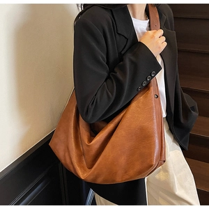 Detailed close-up of a large brown vintage faux leather hobo shoulder bag on a model