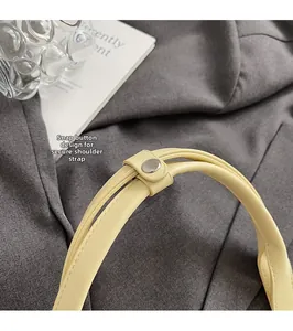 Détail de la bandoulière en cuir jaune pâle avec bouton-pression en métal brillant