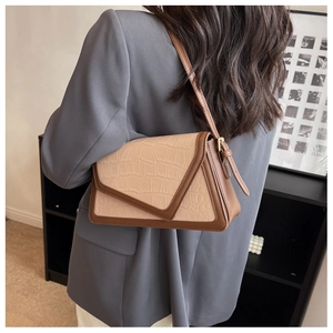 Detail view of the two-tone crocodile pattern shoulder bag worn by a model in a minimal setting