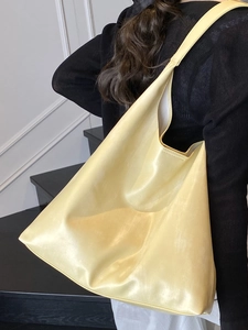 Minimalist light yellow oversized PU leather tote bag shown on model in a modern indoor setting