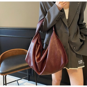 Detailed view of burgundy wax leather tote bag worn by a model for professional daily commute