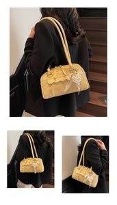 Détail d'un sac jaune vintage avec un nœud en dentelle blanche et charme de perle