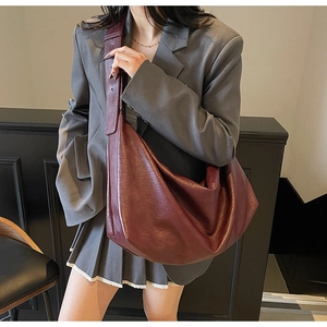 Detail view of large dark red dumpling tote bag worn as a crossbody shoulder bag
