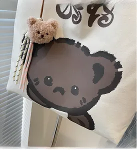 Detail of canvas tote bag showing cute brown bear print and plush bear charm accessory