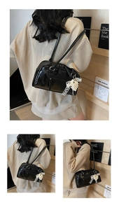 Détail du sac boston en cuir verni noir avec pendentif nœud en dentelle et perles